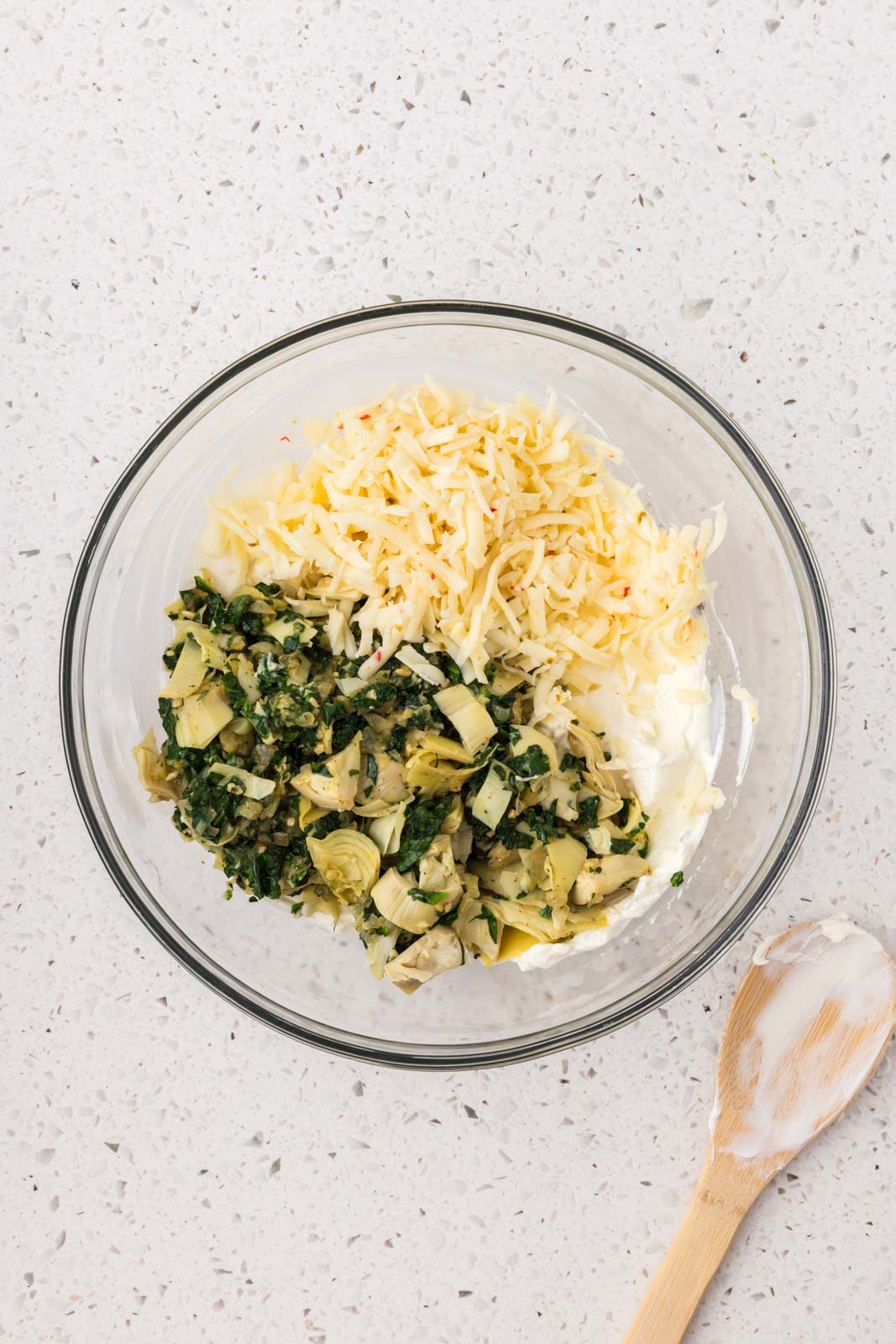 Spinach artichoke mixture and shredded pepper jack added to the bowl. 