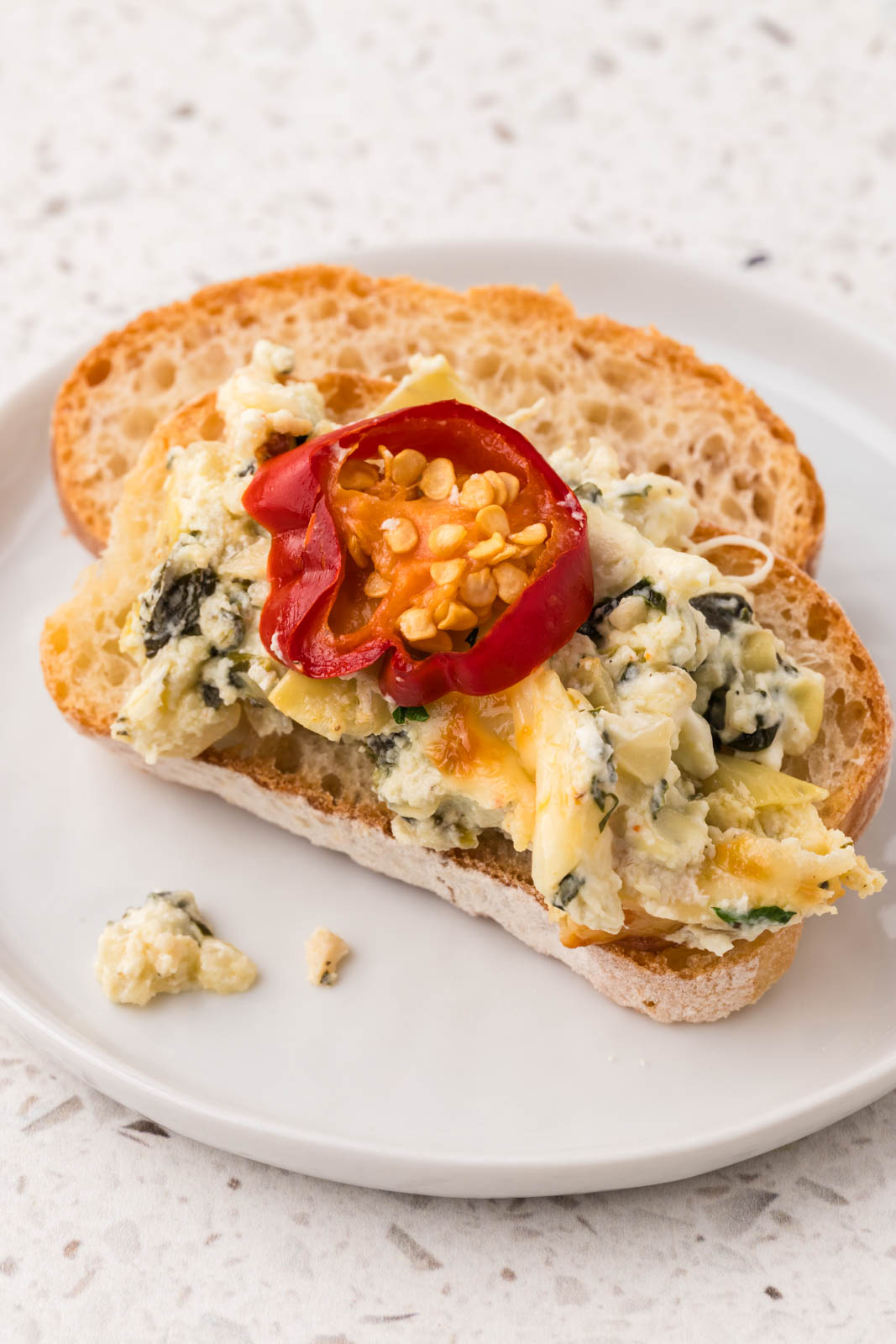 Spicy spinach artichoke dip on a piece of crusty bread. 