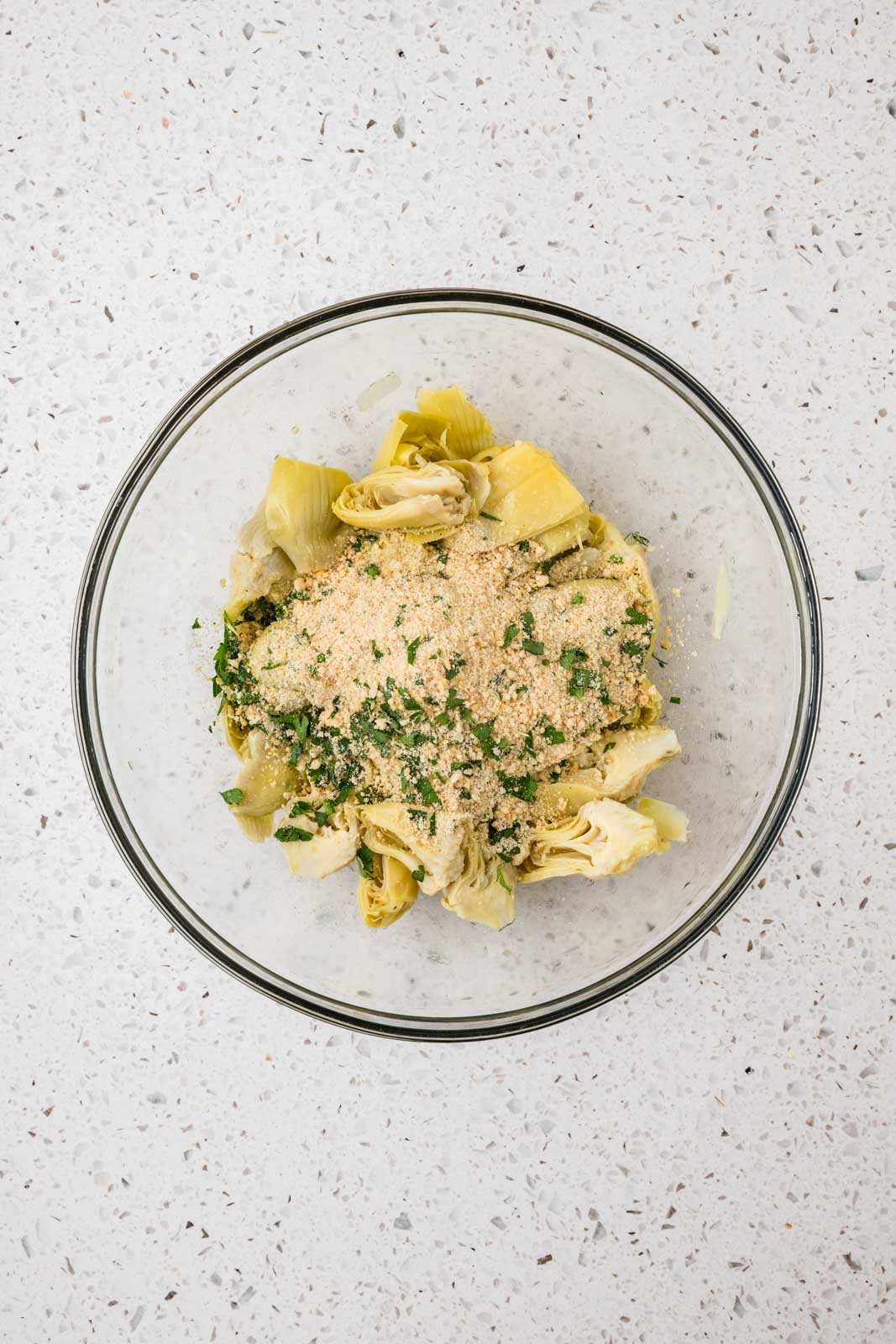 Dry ingredients added to bowl with artichoke hearts. 