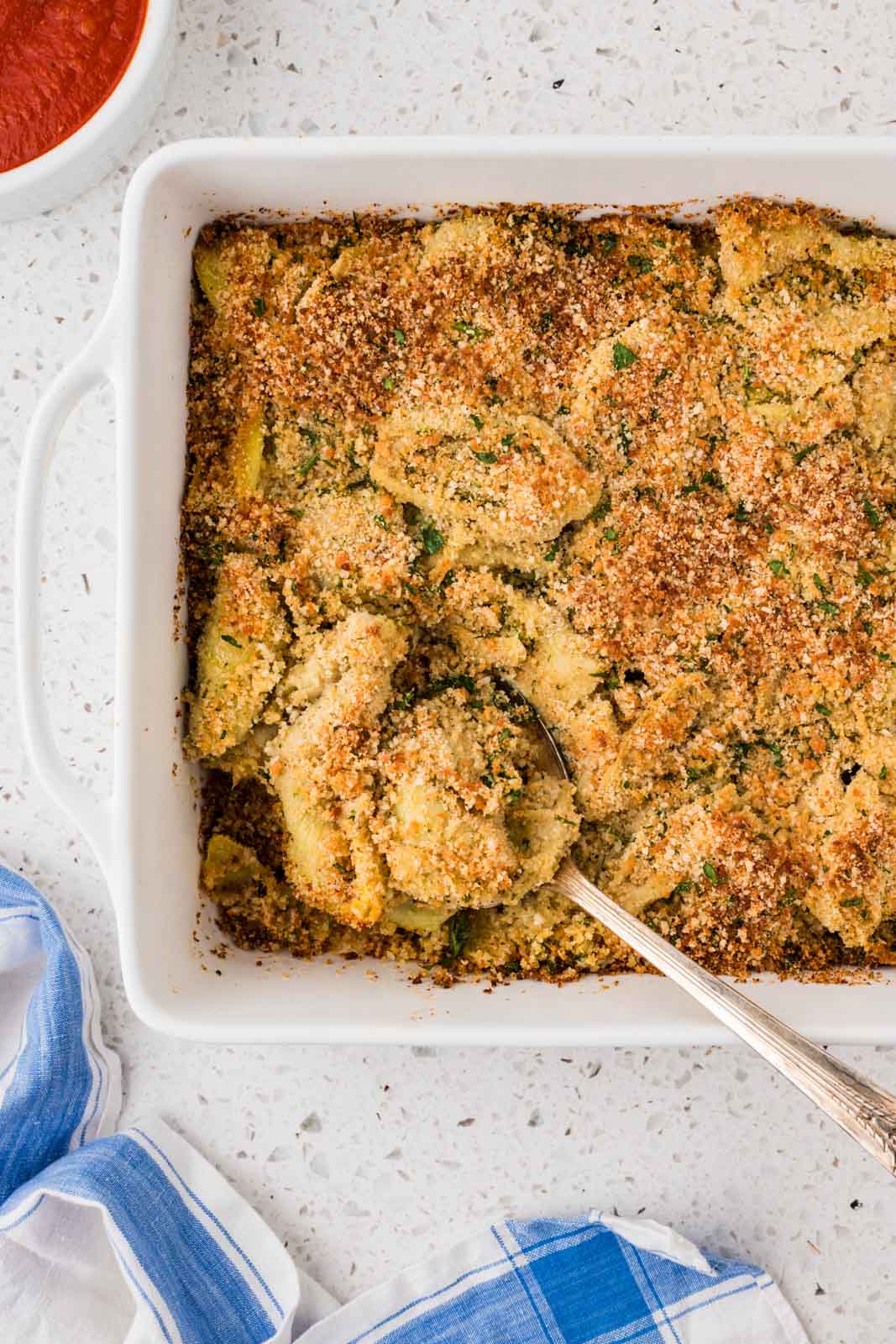 Stuffed Artichoke Casserole with a serving spoon. 