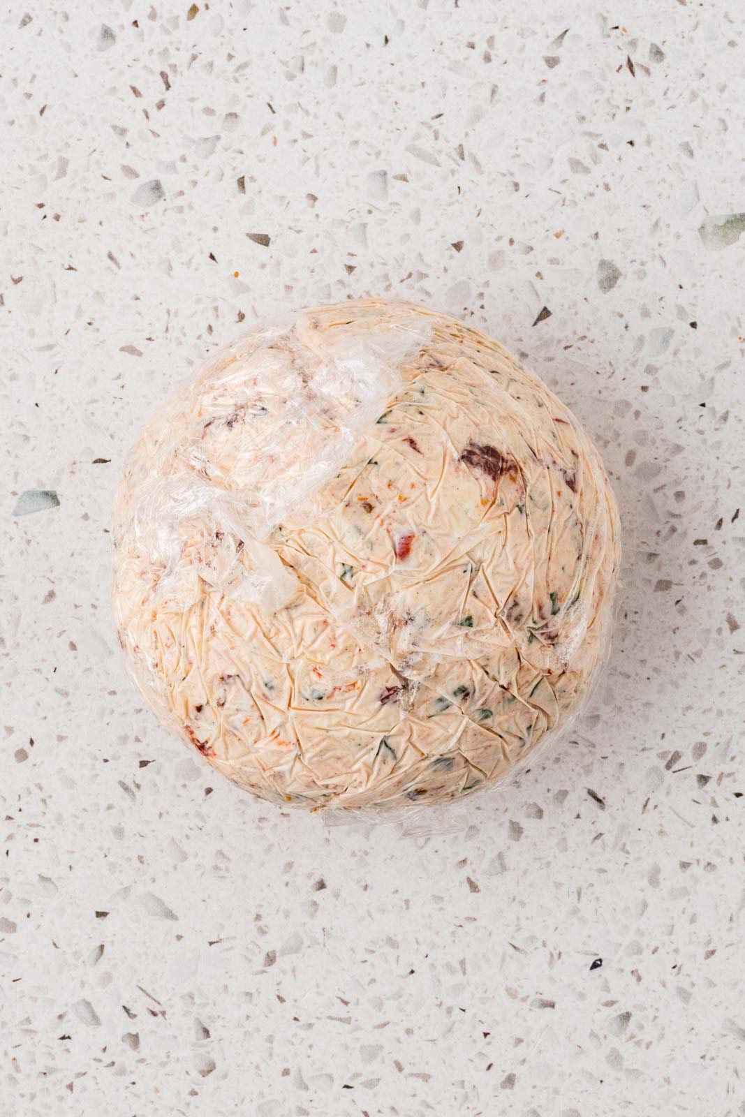 Cheeseball formed and wrapped in plastic wrap.
