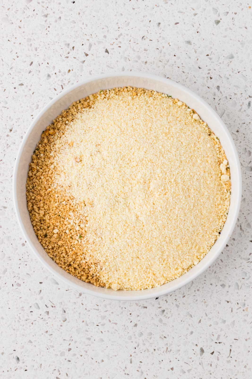 Panko breadcrumbs and parmesan cheese in a shallow bowl.