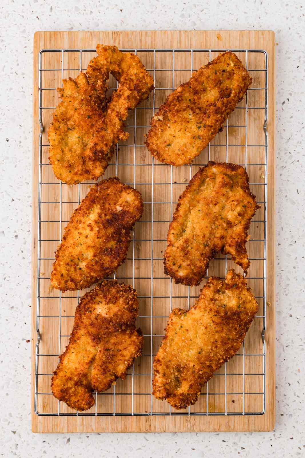 Chicken cutlets fried and on a cooling rack.