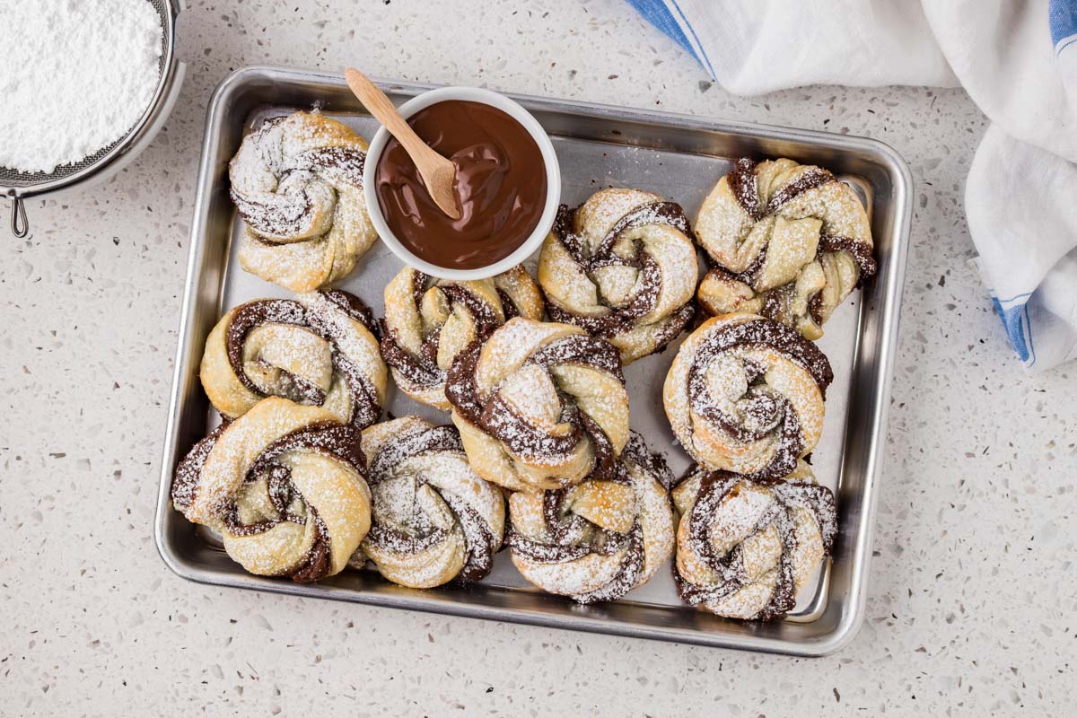 Puff pastries on a platter with extra Nutella for dipping. 