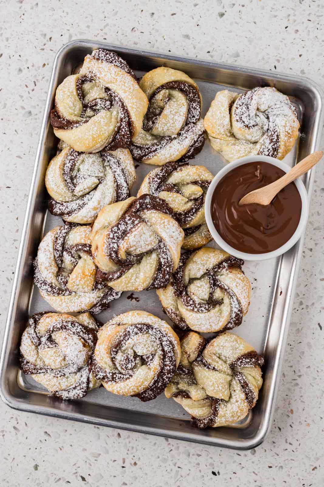 Nutella puff pastries on a platter with extra Nutella. 